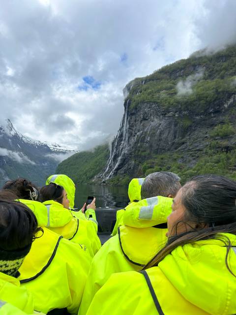 Group of people in yellow jackets with a waterfall in the background.