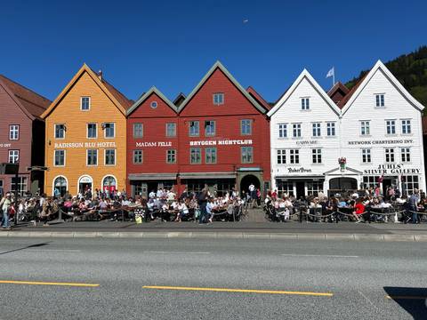 Row of colorful wooden buildings with people walking by.