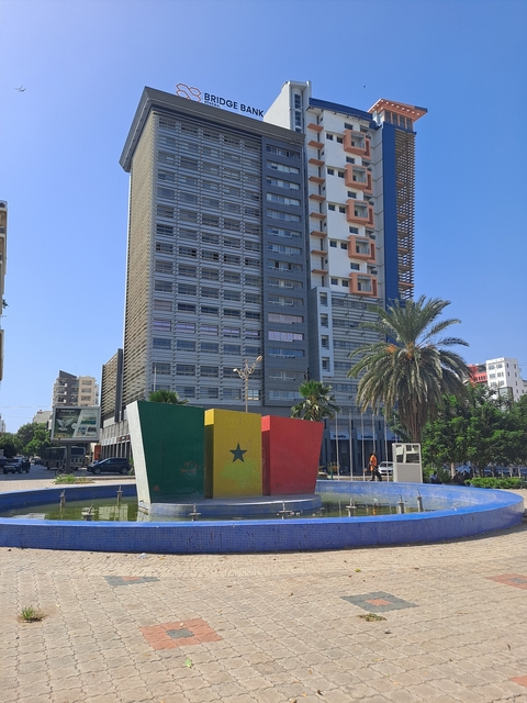 Tall modern building with a Senegal flag sculpture in front.