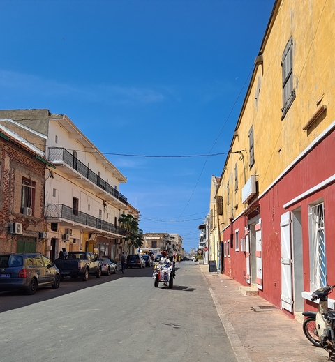       Street scene with colorful buildings under a clear blue sky.
  