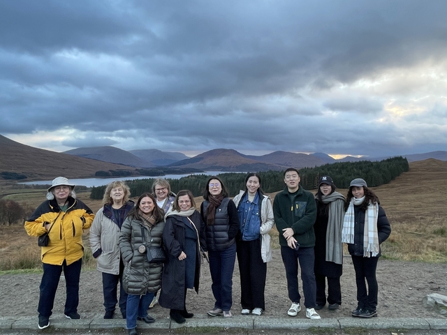       Group of people posing with a scenic mountainous backdrop.
  