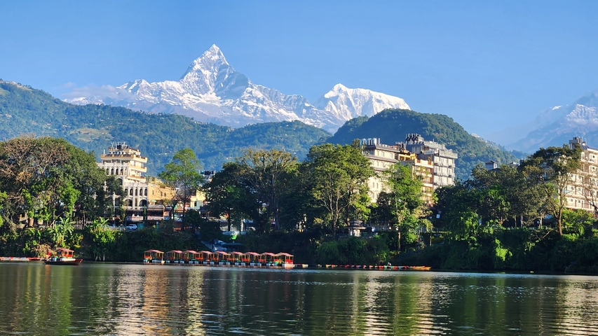       Cityscape with a lake and mountains in the background.
  