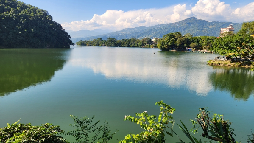       A serene lake surrounded by mountains and greenery.
  