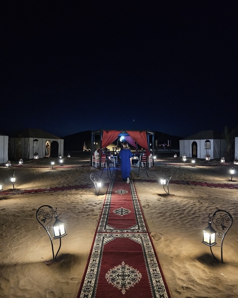 Night view of a desert camp with lights and tents.
