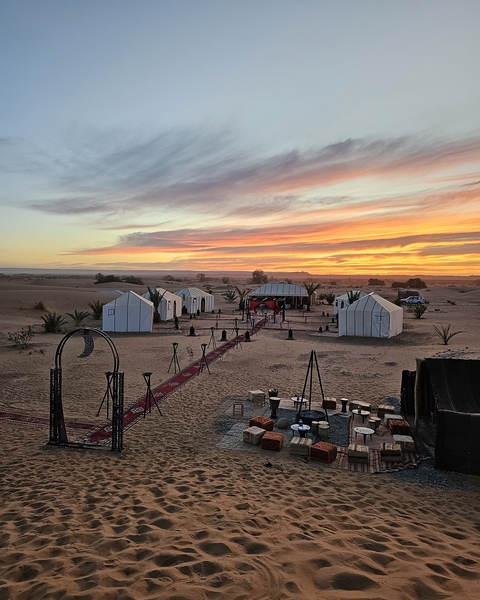 Sunset view of a desert camp with tents.