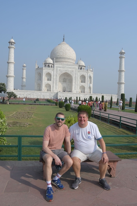       Two tourists posing in front of the Taj Mahal.
  