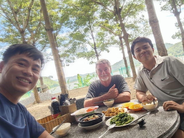       People enjoying a meal outdoors with a scenic backdrop.
  