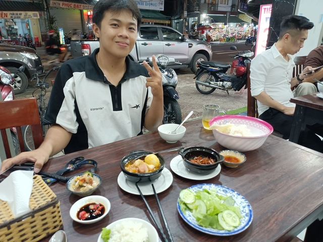       Man enjoying food at a street-side table.
  