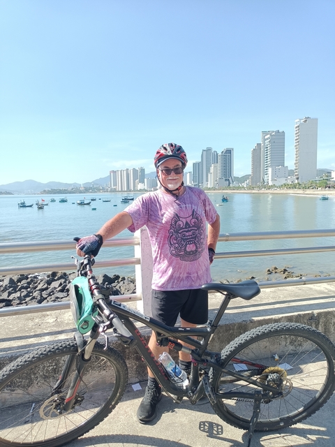       Cyclist posing near a waterfront with high-rise buildings.
  