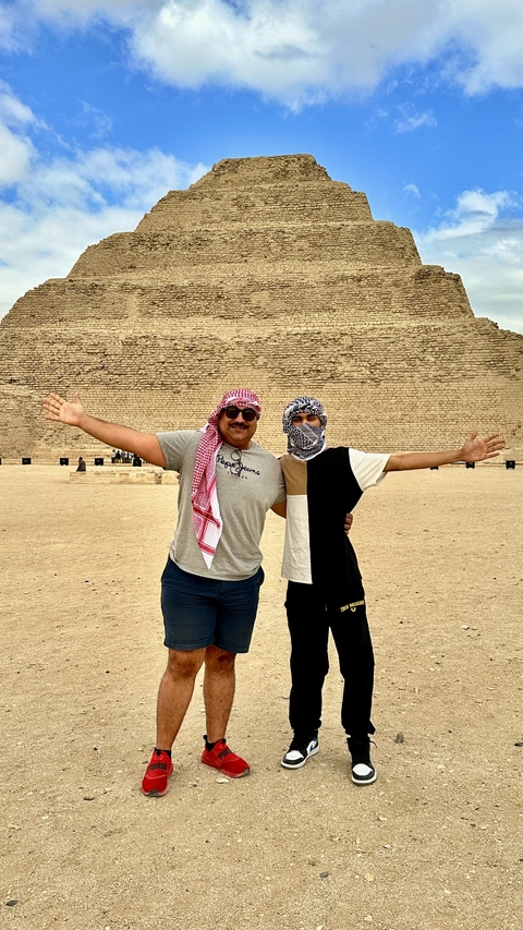       Two people posing in front of a pyramid.
  