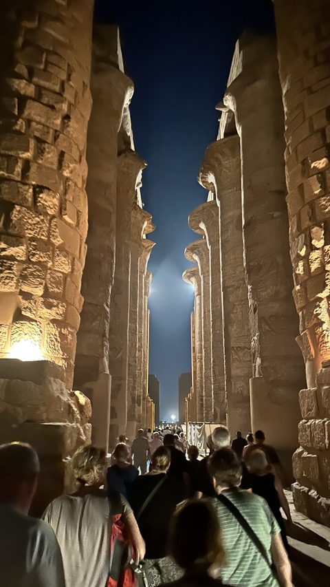       A corridor between large stone columns at night.
  