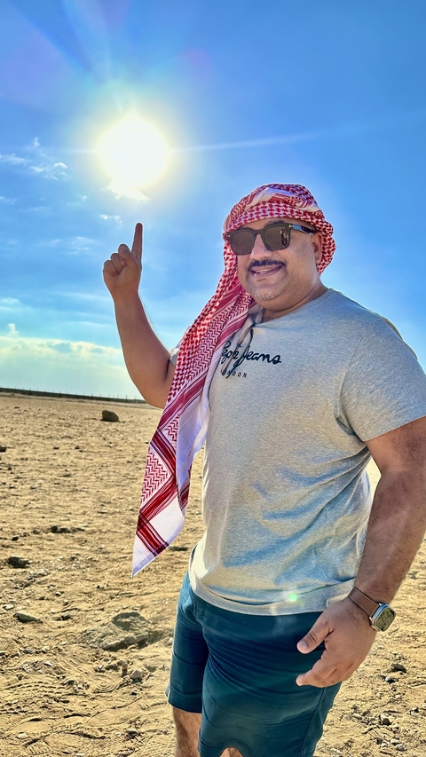       Person standing in the desert wearing a headscarf.
  