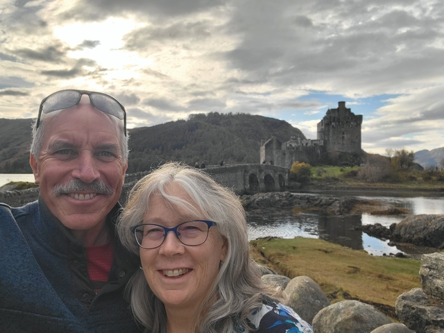 Couple posing with a castle and bridge in the background.