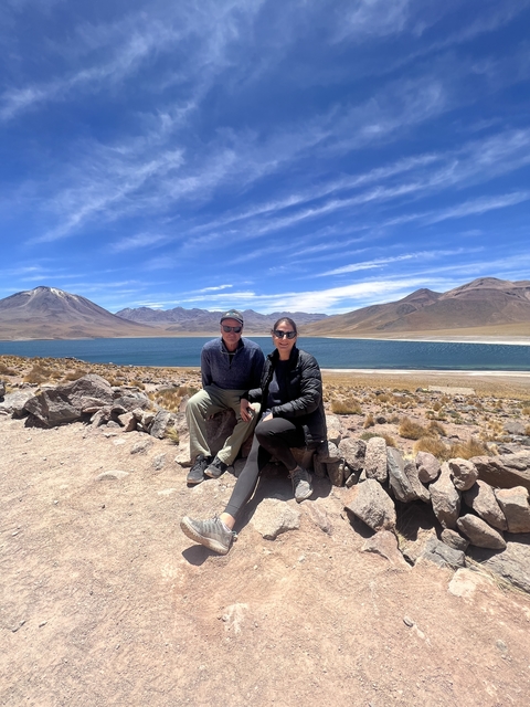       Couple posing in front of a scenic lake with mountains.
  
