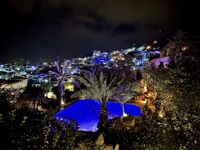       Night view of a city with illuminated buildings and a pool.
  