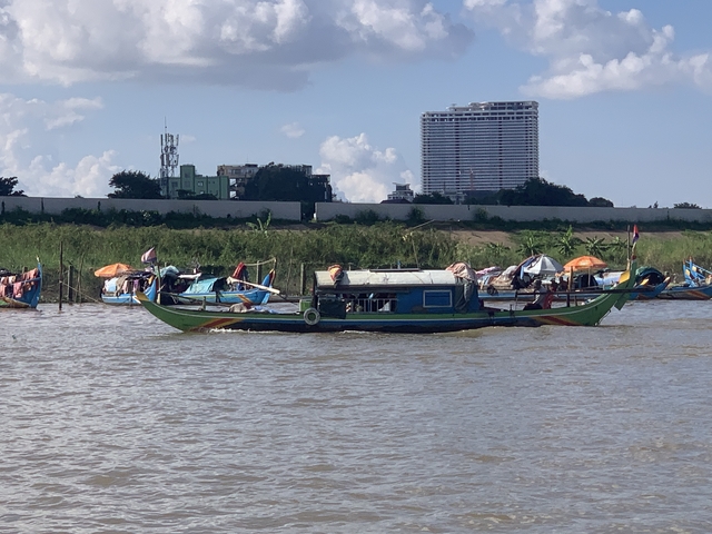       A boat on a river with urban buildings in the background.
  