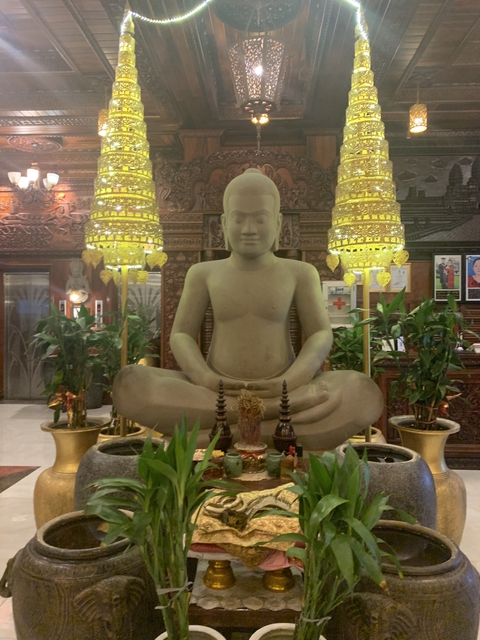 Statue of a seated figure in a decorated room.