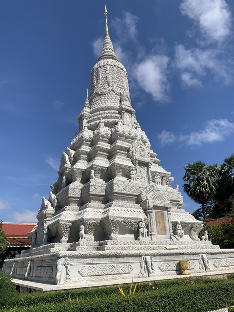       White stone pagoda with intricate carvings against a blue sky.
  