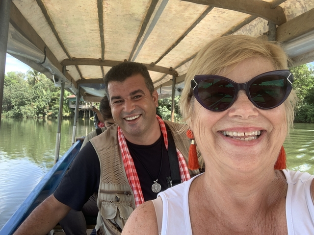       A couple smiling on a boat ride on a river.
  