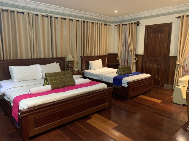 Interior of a hotel room with two beds and wooden decor.