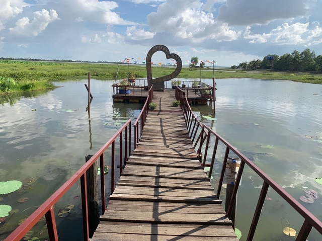       A wooden pier leading to a heart-shaped structure on the water.
  
