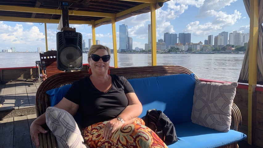       Person sitting on a boat with a view of a river and city skyline.
  