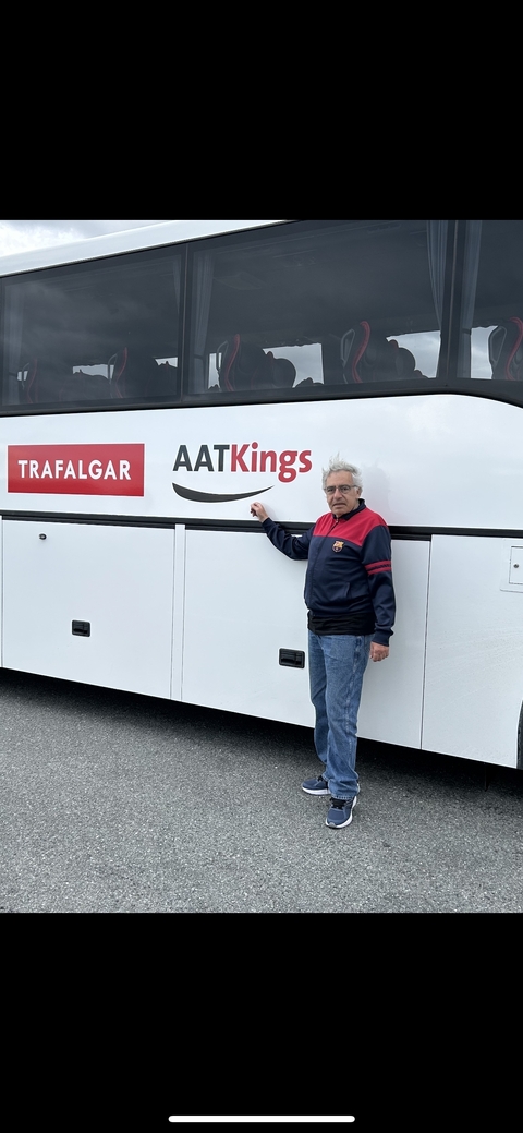 Person standing next to a bus with brand logos.