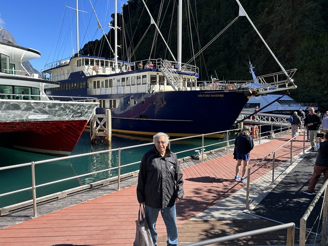 Man standing in harbour with a large blue ship behind.