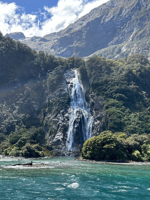 Tall waterfall cascading down a lush green cliff.