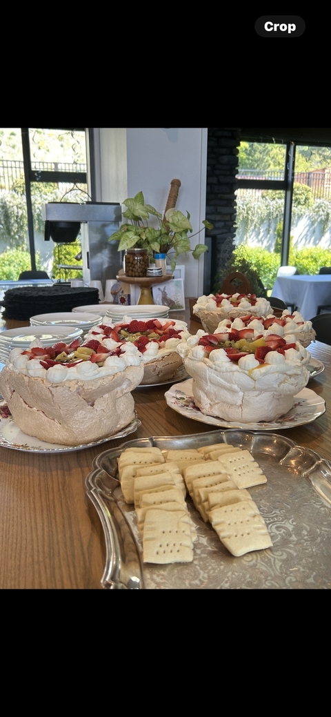 Table filled with decorated pavlovas and fruit.