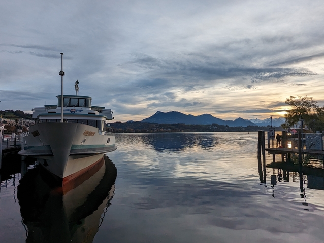 Boat docked at the lake with a mountainous backdrop.