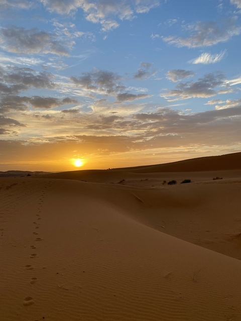 Sunset over desert dunes with a clear sky.