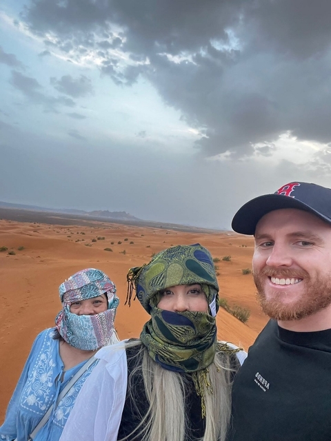       People with headscarves in front of desert landscape.
  