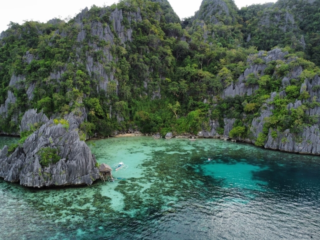 Aerial view of a tropical bay with clear water and lush vegetation.