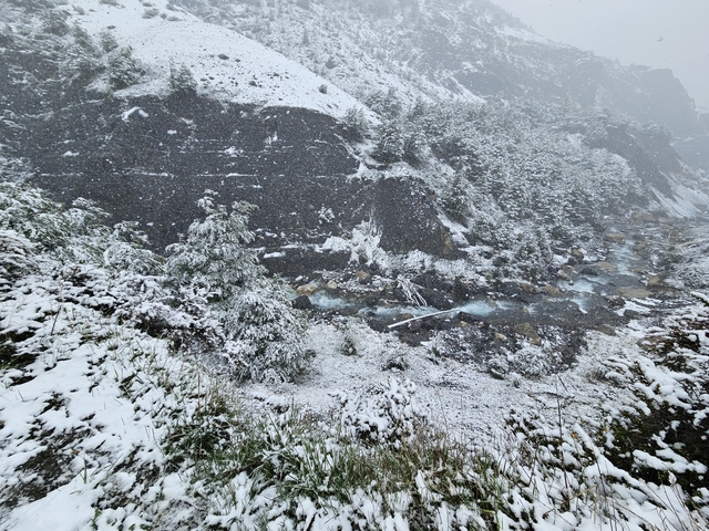 Snowy river landscape with rocky mountain slopes.