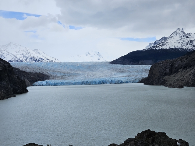       A vast glacier meeting a lake in a mountainous area.
  