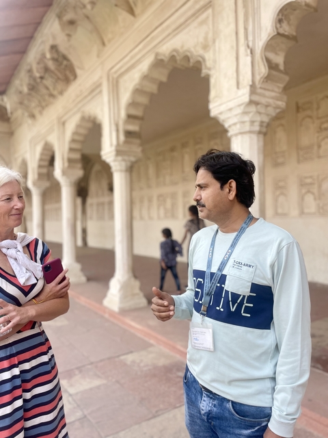 Two people having a friendly conversation in a columned walkway.
