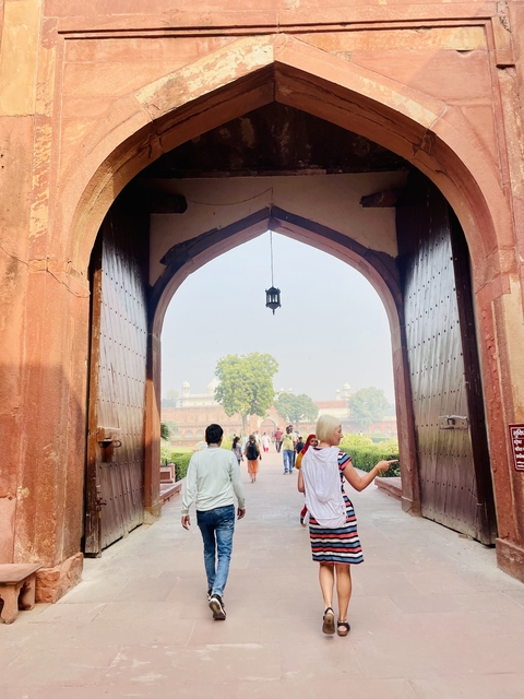 People walking through a large doorway onto a scenic garden area.