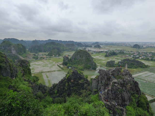 Wide view of a valley with rice fields and small hills.