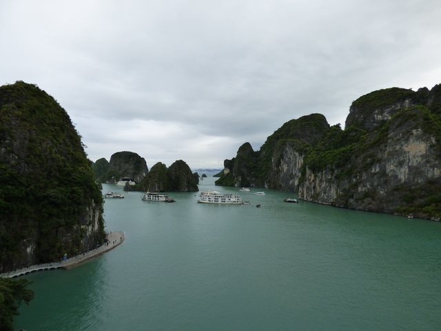       Aerial view of boats navigating between limestone karsts.
  