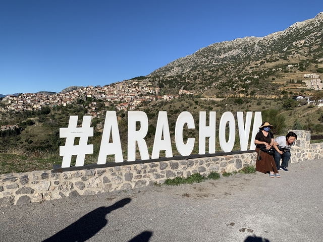       People sitting by a large hashtag sign 'ARACHOVA'.
  