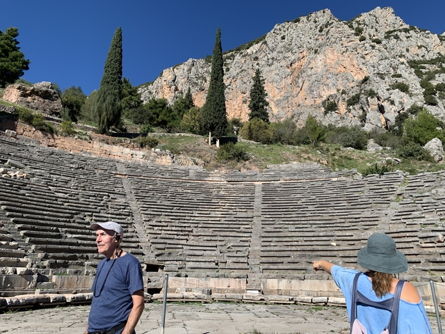       Ancient theatre with tourists exploring.
  