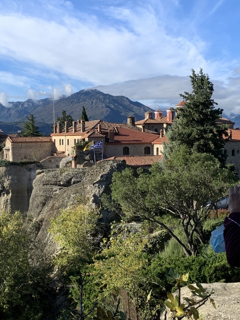       Monastery on a rocky hill with Greek flag.
  