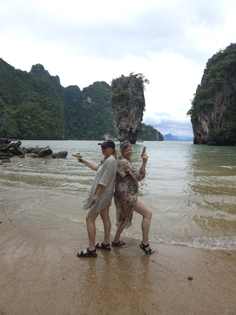 Two women posing like Bond girls on a beach with limestone cliffs.