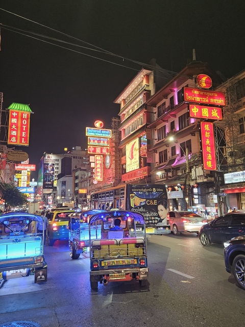 Vibrant street with colorful neon signs at night.