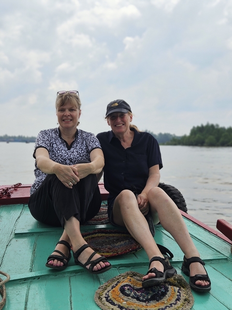       Two friends relaxing on a boat on a calm river.
  