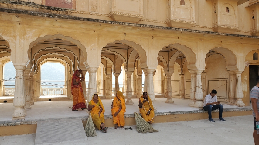       People sitting in a historic building with arches.
  