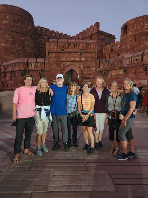       Group of people in front of a red sandstone fort's gate.
  