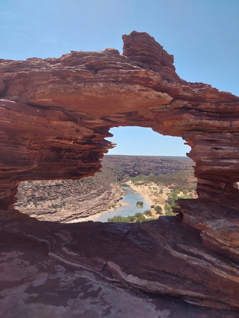       Natural rock arch framing a distant river view.
  