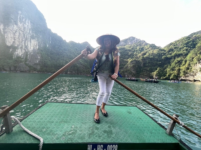       Woman standing on a boat with scenic limestone cliffs in the background.
  
